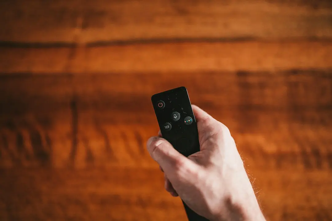 A hand pointing a TV remote, as when browsing KenoaTV channels on a Fire TV Stick