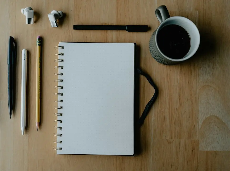 A blank notebook, pens and a cup of coffee on a wooden desk, ready for an IPTV service checklist